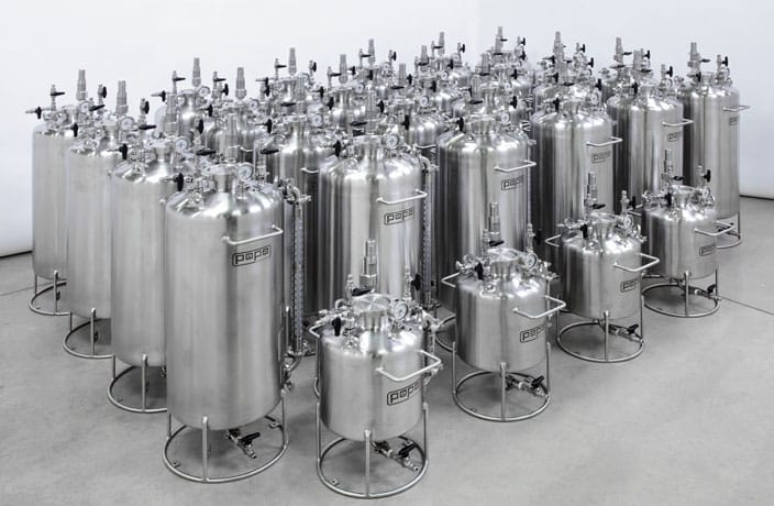 a group of stainless steel tanks lined up in a room.