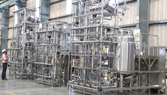 a woman standing in front of a machine in a factory