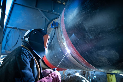 Industrial welder applying controlled weld cooling methods to thick steel section