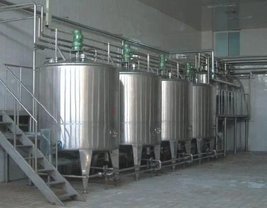 A row of stainless steel tanks sitting inside of a building.