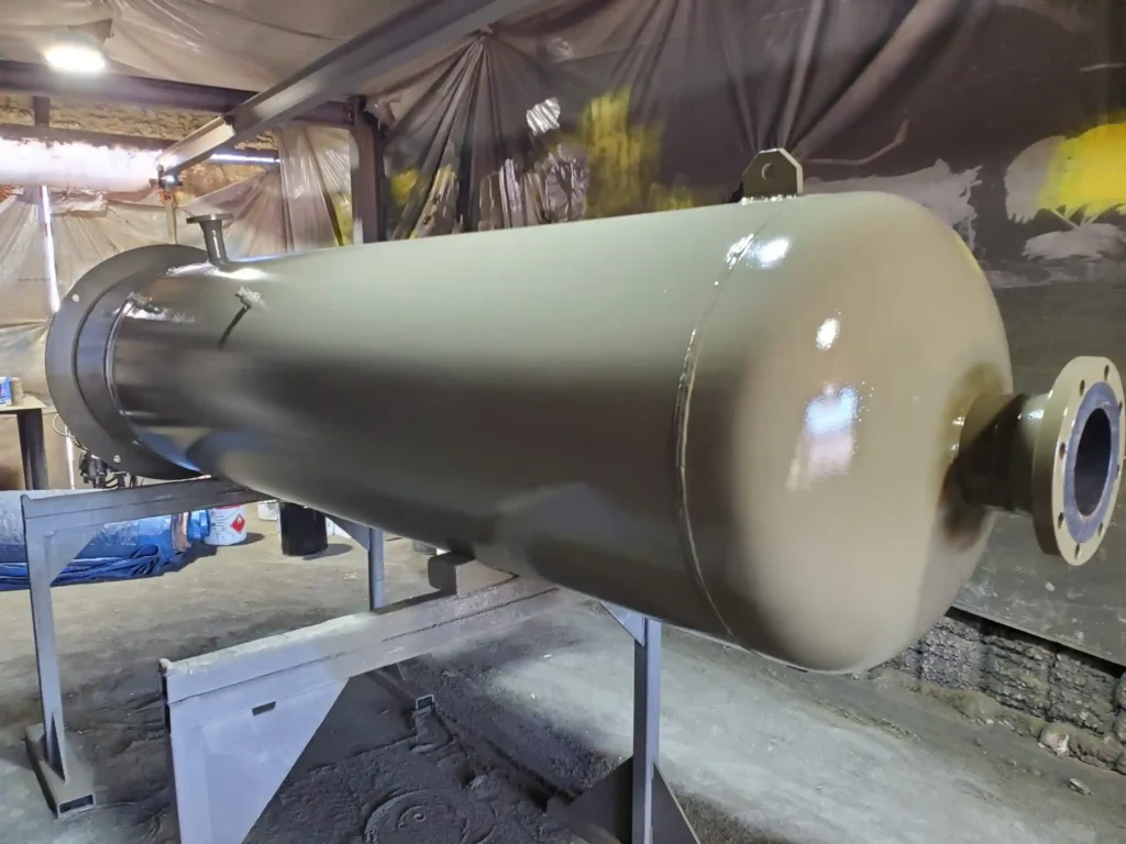 Horizontal ASME pressure vessel with protective coating during fabrication in an industrial workshop.