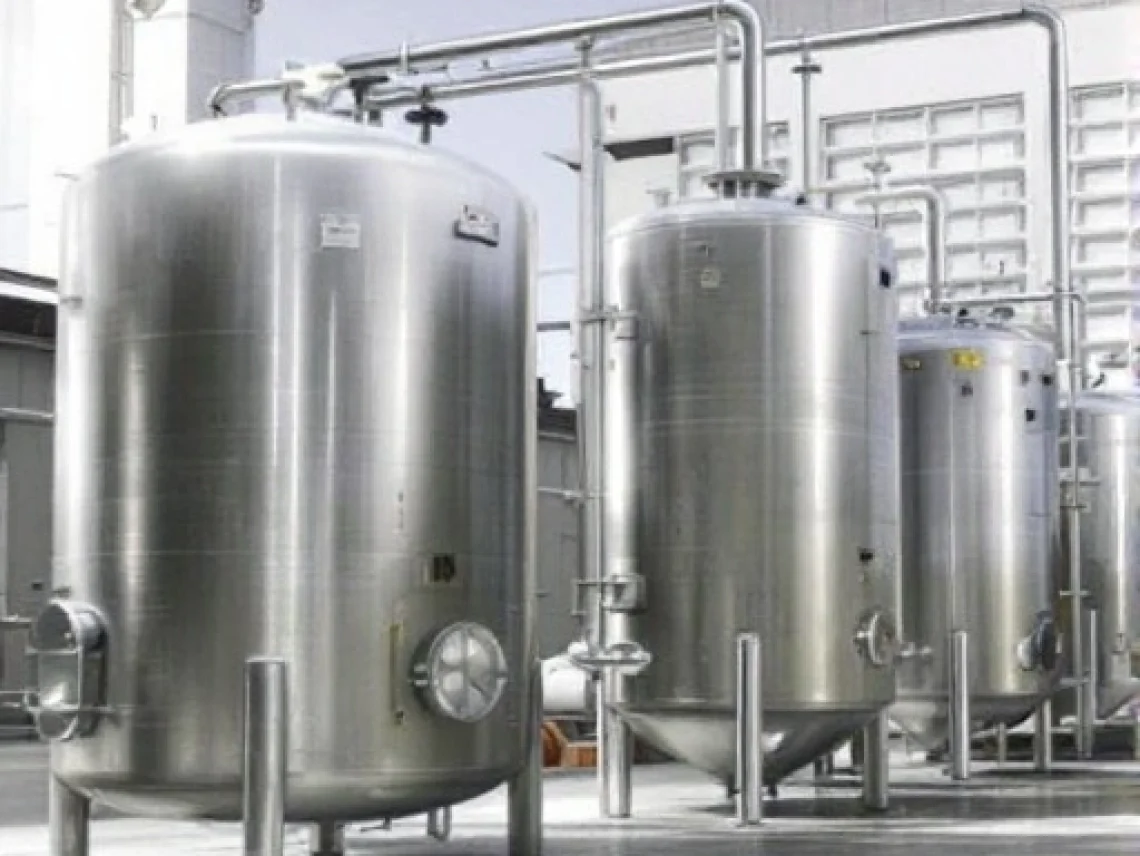 Stainless steel pressure vessels in an industrial facility with piping and concrete flooring