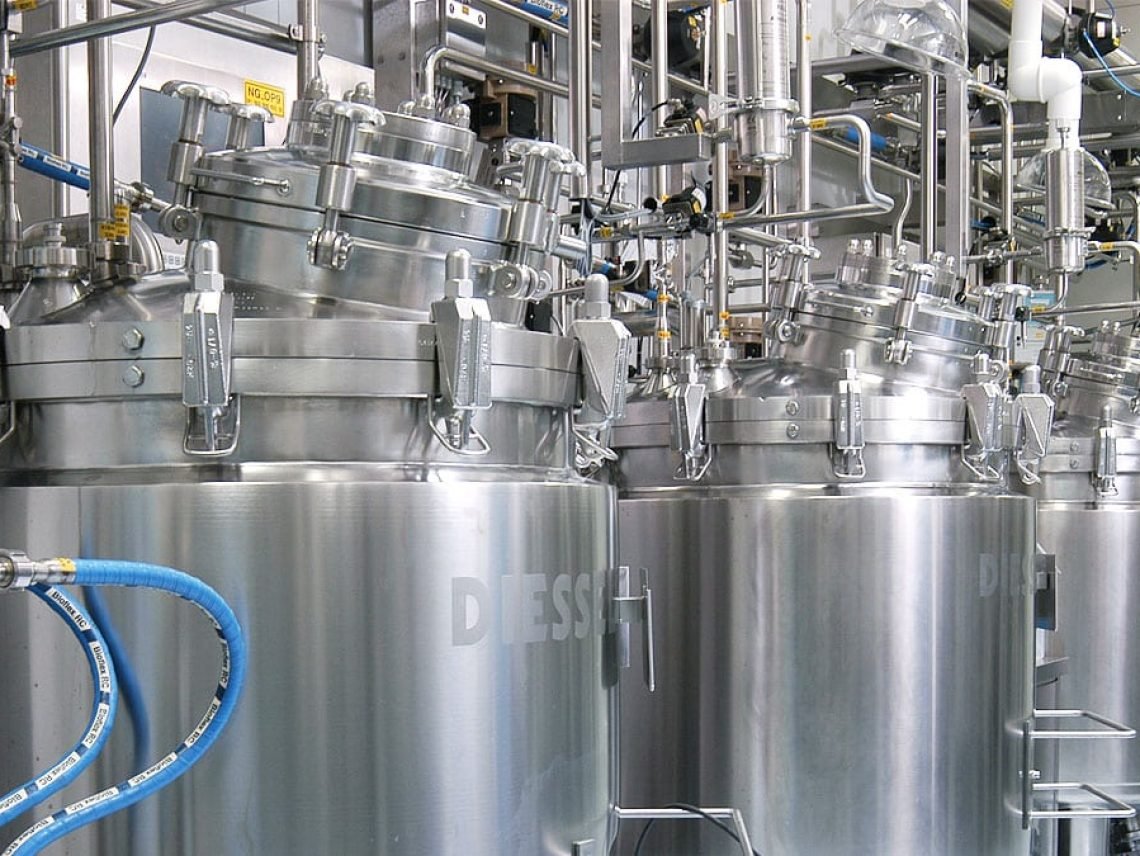 a bunch of stainless steel tanks in a factory