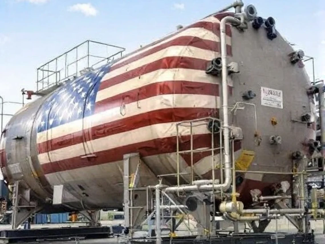 ASME pressure vessel painted with an American flag, mounted on a platform with piping and ladders outdoors